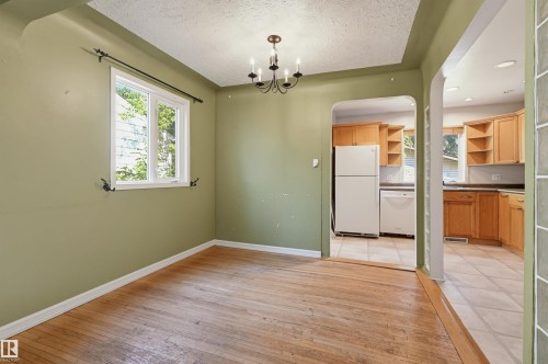 Open concept dining area featuring wood-finish flooring, a single window with exterior light, and a black metal chandelier - 7754 80 Avenue Nw, Edmonton, AB - Indoor Photo Showing Other Room