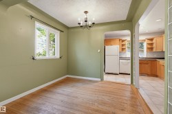 Open concept dining area featuring wood-finish flooring, a single window with exterior light, and a black metal chandelier - 