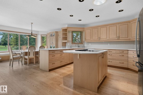 Open-concept kitchen and dining area featuring light wood-finish cabinetry, a central island with a built-in cooktop, and light wood-finish flooring - 120 Ironwood Place Nw, Edmonton, AB - Indoor Photo Showing Kitchen