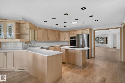 Kitchen featuring wood-finish flooring, light wood cabinetry, white countertops, a stainless steel refrigerator, and built-in wall oven with stovetop - 120 Ironwood Place Nw, Edmonton, AB - Indoor Photo Showing Kitchen