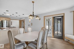 Dining area with light wood-finish flooring, featuring a contemporary chandelier, recessed ceiling lighting, and a built-in window bench - 