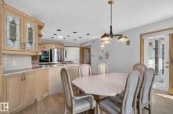 Dining area with light-toned wood-finish flooring, a multi-light chandelier, and double glass-paneled doors - 