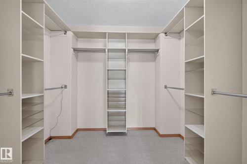 Spacious closet with built-in shelving units, multiple hanging rods, and a central tiered shelving system - 120 Ironwood Place Nw, Edmonton, AB - Indoor With Storage