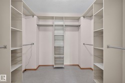 Spacious closet with built-in shelving units, multiple hanging rods, and a central tiered shelving system - 