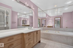 Bathroom featuring a light wood-finish vanity with a white countertop and integrated sink, full-wall mirrors, a built-in bathtub with tiled surround, a separate shower enclosure, and recessed ceiling lighting - 