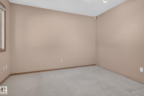 Carpeted room featuring neutral wall paint, wood trim, and a window with wood-frame blinds - 120 Ironwood Place Nw, Edmonton, AB - Indoor Photo Showing Other Room