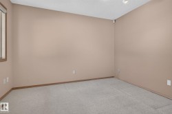 Carpeted room featuring neutral wall paint, wood trim, and a window with wood-frame blinds - 