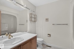 Bathroom featuring a vanity with wood-finish cabinetry, a white countertop, and an integrated white sink - 