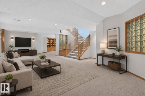 Spacious lower-level living area featuring recessed lighting, light-toned carpeting, and a wood-finish staircase with natural wood railings - 120 Ironwood Place Nw, Edmonton, AB - Indoor Photo Showing Living Room