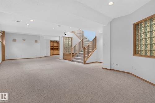 Open-concept lower level featuring recessed lighting, a carpeted floor, and a light wood staircase with a matching railing - 120 Ironwood Place Nw, Edmonton, AB - Indoor Photo Showing Other Room