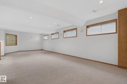 Expansive carpeted room featuring recessed lighting, a glass block window, multiple standard windows with blinds, wood trim, and built-in cabinetry - 