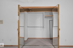 Mirrored bi-fold closet doors with brass-tone framing open to reveal an organized interior with multiple hanging rods and a shelf - 