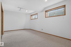 Carpeted room featuring two windows with wood trim, track lighting, and a neutral wall palette - 