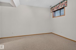 Carpeted room featuring white walls, light wood-finish trim, and a window with blinds - 