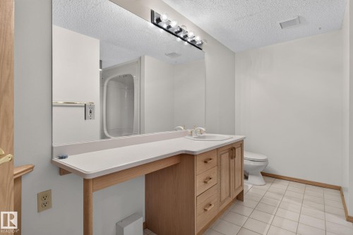 Bathroom vanity featuring a light wood cabinet with storage, white countertop, and integrated sink - 120 Ironwood Place Nw, Edmonton, AB - Indoor Photo Showing Bathroom