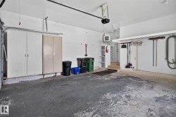 Two-car garage featuring built-in storage cabinets, overhead shelving, and a concrete floor - 