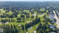 Expansive golf course and surrounding residential area featuring mature trees and a tranquil pond - 