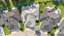 Shingled roofline over a multi-level residence with a paved driveway and landscaped grounds - 