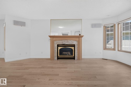 Fireplace with a natural wood mantel and stone surround - 120 Ironwood Place Nw, Edmonton, AB - Indoor Photo Showing Living Room With Fireplace