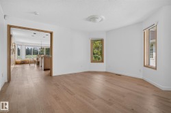 Spacious interior room with light wood-finish flooring and white walls - 