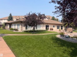 Stucco exterior structure with a low-pitch roof and multiple large windows - 