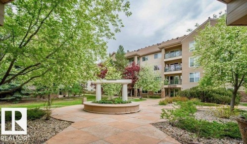 Central courtyard with a decorative fountain, surrounded by mature trees and landscaping - #209 8912 156 St Nw, Edmonton, AB - Outdoor
