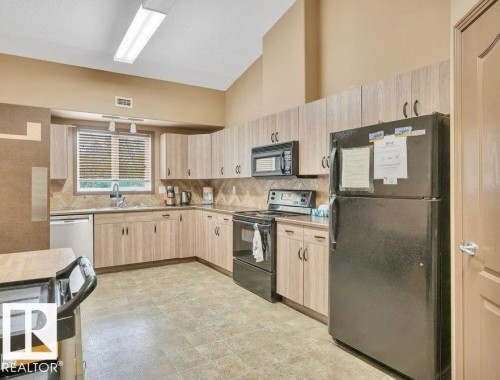 Kitchen featuring light wood-finish cabinetry, tile flooring, and a tile backsplash - #209 8912 156 St Nw, Edmonton, AB - Indoor Photo Showing Kitchen