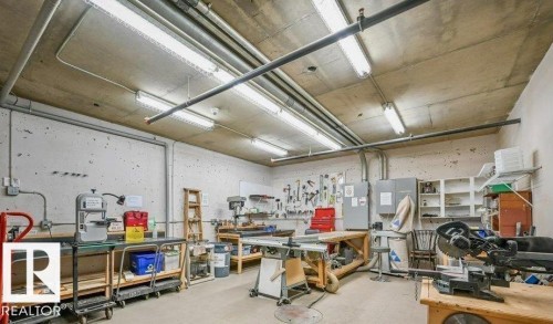Concrete walls and ceiling with exposed ductwork, fluorescent lighting, and built-in shelving - #209 8912 156 St Nw, Edmonton, AB - Indoor