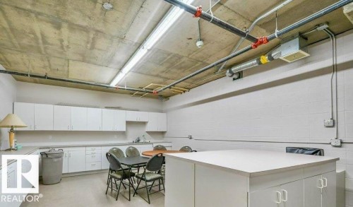 Exposed ceiling with ductwork and piping, white block wall, white cabinetry with silver hardware, recessed sink, and white countertops - #209 8912 156 St Nw, Edmonton, AB - Indoor
