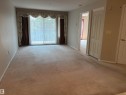 Spacious room featuring neutral carpeting, light-toned walls, and a wide sliding glass door - #209 8912 156 St Nw, Edmonton, AB  - Indoor Photo Showing Other Room 