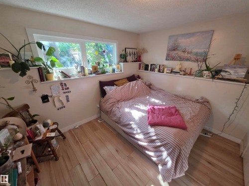 Room featuring wood-finish flooring, a wide window with a deep sill, and built-in wall shelving - 38 Greenwood Drive, Spruce Grove, AB - Indoor Photo Showing Bedroom