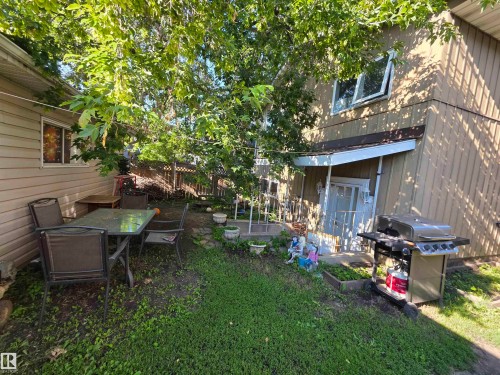 Expansive rear yard featuring mature trees, a small patio area with a glass-top table, and a green space - 38 Greenwood Drive, Spruce Grove, AB - Outdoor With Deck Patio Veranda