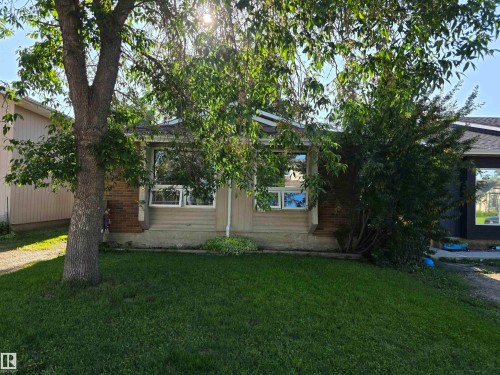 Front exterior featuring a well-maintained lawn, mature trees, and a beige siding facade - 38 Greenwood Drive, Spruce Grove, AB - Outdoor