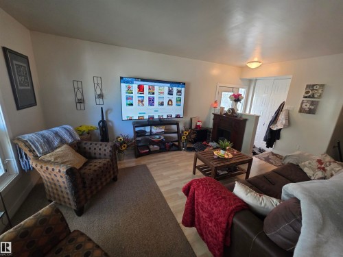 Open-concept living area featuring light-toned flooring, a fireplace with a dark wood mantel, and a ceiling-mounted light fixture - 38 Greenwood Drive, Spruce Grove, AB - Indoor Photo Showing Living Room