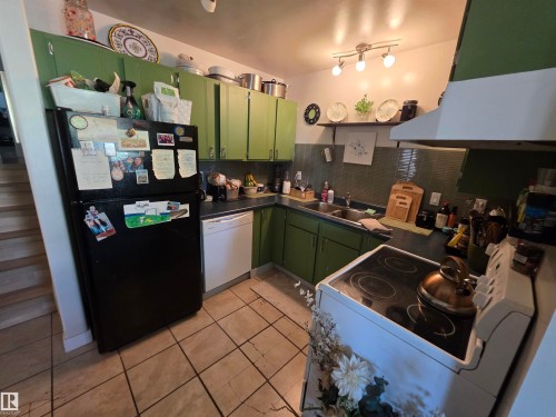 Kitchen featuring green cabinetry, tile flooring, and a track lighting fixture - 38 Greenwood Drive, Spruce Grove, AB - Indoor Photo Showing Kitchen With Double Sink