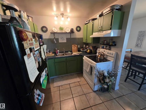 Kitchen featuring green cabinetry, tile flooring, track lighting, a dedicated range area with hood, and a dark countertop - 38 Greenwood Drive, Spruce Grove, AB - Indoor Photo Showing Kitchen With Double Sink