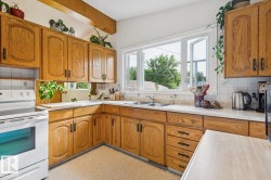 L-shaped kitchen featuring wood cabinetry, laminate countertops, and a double-basin stainless steel sink under a large window - 