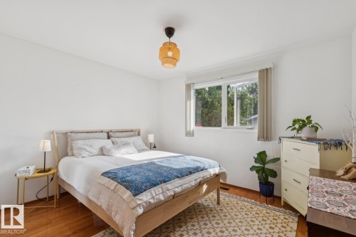 Bright bedroom featuring wood-finish flooring and a large window - 12835 91 Street Nw, Edmonton, AB - Indoor Photo Showing Bedroom