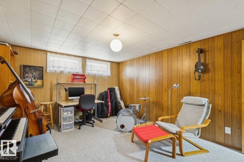 Room featuring wood paneling, a drop ceiling, and two windows with white curtains - 12835 91 Street Nw, Edmonton, AB - Indoor