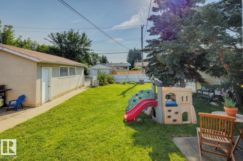 Expansive backyard featuring a large green lawn, mature trees, a concrete patio, and a detached structure with multiple windows - 12835 91 Street Nw, Edmonton, AB - Outdoor
