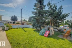 Expansive backyard featuring a manicured lawn, established trees, and a white picket fence - 