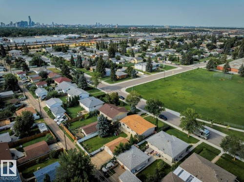 Residential neighborhood featuring a large green space, mature trees, paved streets, and a distant cityscape - 12835 91 Street Nw, Edmonton, AB - Outdoor With View