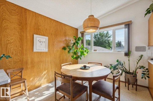 Dining area featuring a wood-paneled accent wall, a large window, and a woven pendant light fixture - 12835 91 Street Nw, Edmonton, AB - Indoor Photo Showing Dining Room