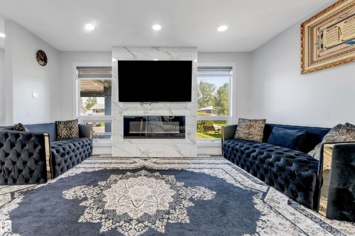 Living area featuring a floor-to-ceiling fireplace with marble-look surround, integrated linear fireplace unit, and built-in media space - 7419 33 Avenue Nw, Edmonton, AB - Indoor Photo Showing Living Room With Fireplace