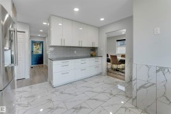 Contemporary kitchen with white high-gloss cabinetry, dark countertops, and a gray subway tile backsplash - 