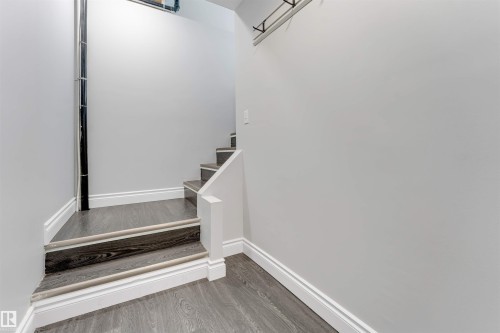 Staircase featuring dark wood-finish treads with light-toned nosing, white risers, and a partial white railing - 7419 33 Avenue Nw, Edmonton, AB - Indoor Photo Showing Other Room