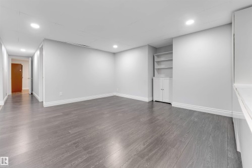 Spacious room featuring wood-finish flooring, recessed lighting, and white baseboards - 7419 33 Avenue Nw, Edmonton, AB - Indoor Photo Showing Other Room