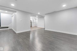 Spacious open-concept room featuring gray wood-finish flooring, recessed lighting, white baseboards, and painted walls - 