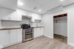 Kitchen featuring white flat-panel cabinetry, wood-finish countertops, and stainless steel appliances including a double oven range and range hood - 