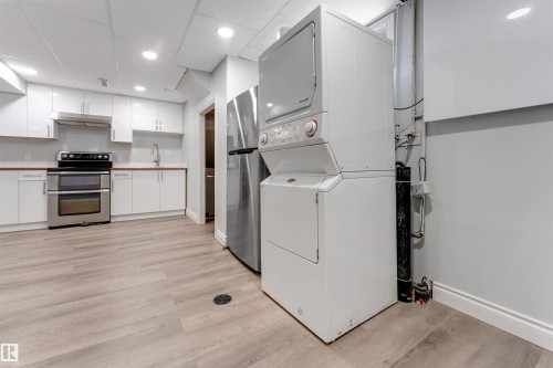 Full kitchen featuring white cabinetry, stainless steel appliances, wood-finish countertops, and wood-finish flooring - 7419 33 Avenue Nw, Edmonton, AB - Indoor Photo Showing Laundry Room